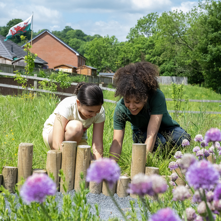 Close up of an MWT member of staff gardening with a young girl at a community garden