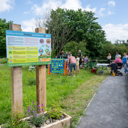 Visitor sign at a community wildlife garden, people in the background